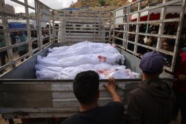 People surround a truck carrying the bodies of victims.