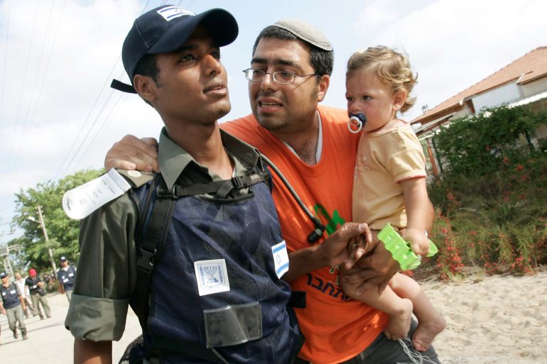 A settler carrying his child tries to convince an Israeli policemen to let them stay in the Jewish settlement of Ganei Tal, southern Gaza Strip. A settler carrying his child tries to convince an Israeli policemen to let them stay in the Jewish settlement of Ganei Tal, in the Gush Katif settlement bloc, in the southern Gaza Strip, August 17, 2005. Israeli troops began the forced evacuation on Wednesday of thousands of Jewish settlers gripped by rage and anguish over their eviction from the Gaza Strip after nearly four decades of occupation. REUTERS/Jerry Lampen