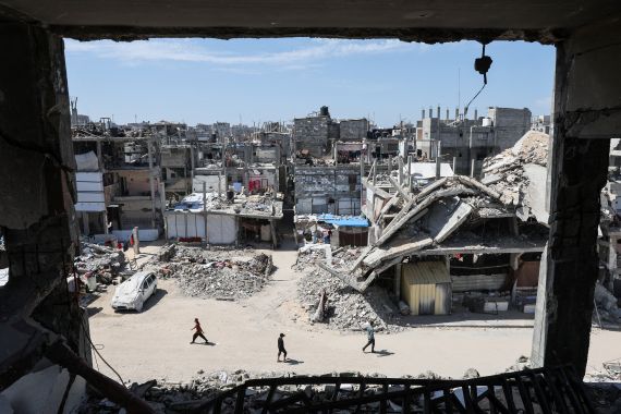 Palestinians walk near the rubble of destroyed houses in Khan Younis, in southern Gaza [Ramadan Abed /Reuters]