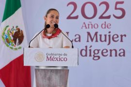 Claudia Sheinbaum at a podium in front of a Mexican flag and a sign that reads, "2025 Año de la Mujer Indigena"