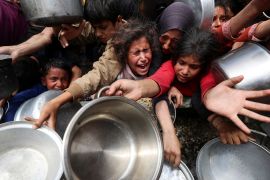 Palestinians wait to receive food cooked in Gaza