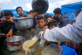 Palestinians, including children, line up to receive hot meals distributed by charities.