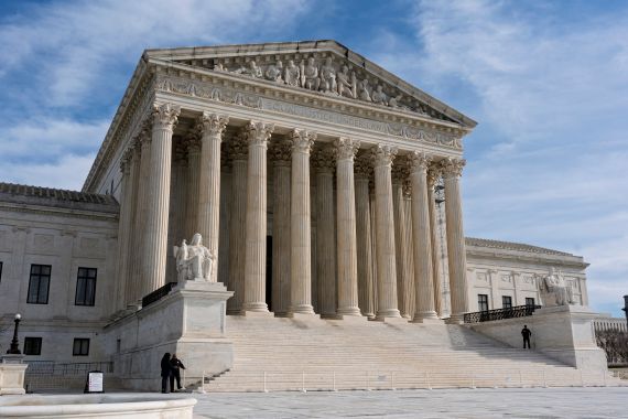 The US Supreme Court building, seen on a cloudy, blue-sky day.